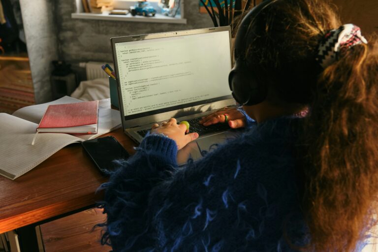 Ein junges Mädchen von hinten, dass an einem Laptop sitzt und programmiert