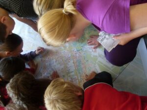 Mehrere Kinder, die über einem Stadtplan hocken und diesen genau inspizieren