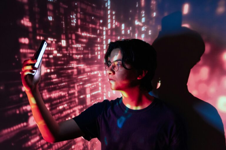 Ein Jugendlicher starrt auf ein Smartphone und wird dabei mit einer projizierten virtuellen Umgebung beleuchtet
