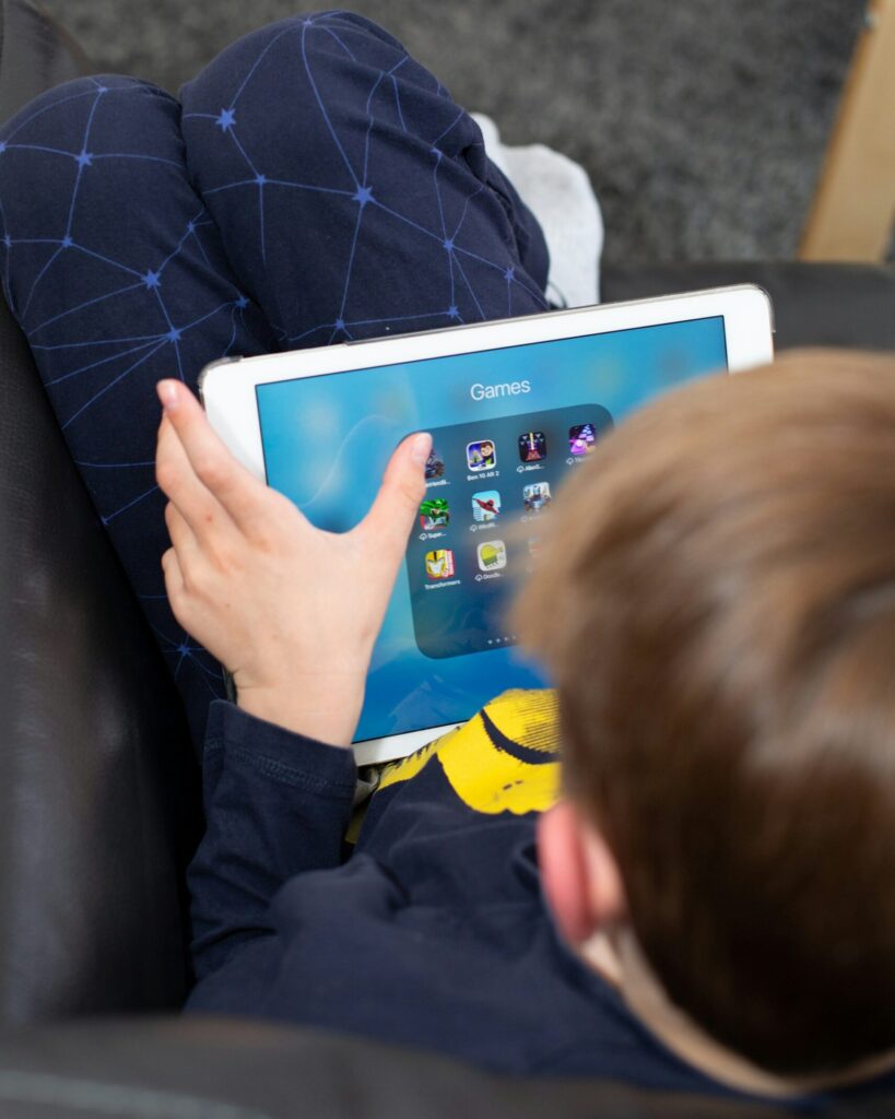 Ein Kind sitzt vor einem iPad und hat die Kategorie "Games" geöffnet.