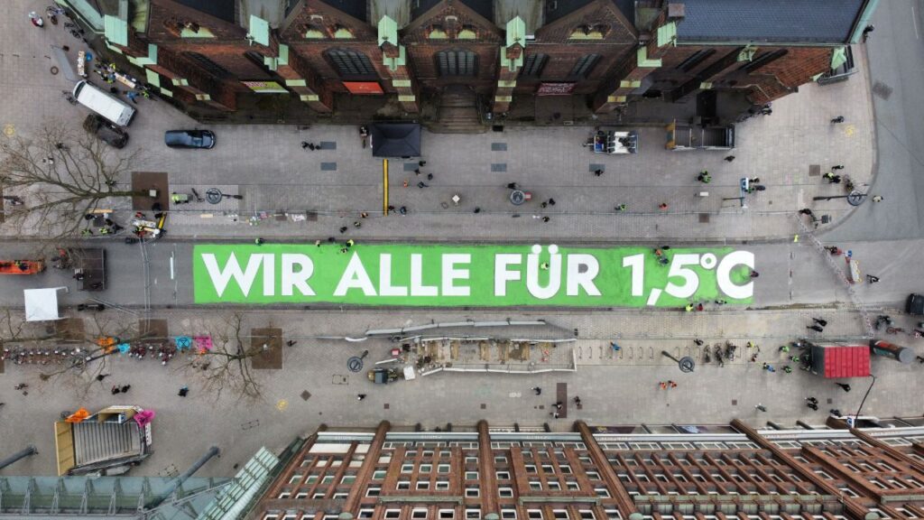 Demo von Fridays for Future für 1,5 Grad Klimaziel. Ein Banner von oben fotografiert zwischen Hochhäusern.