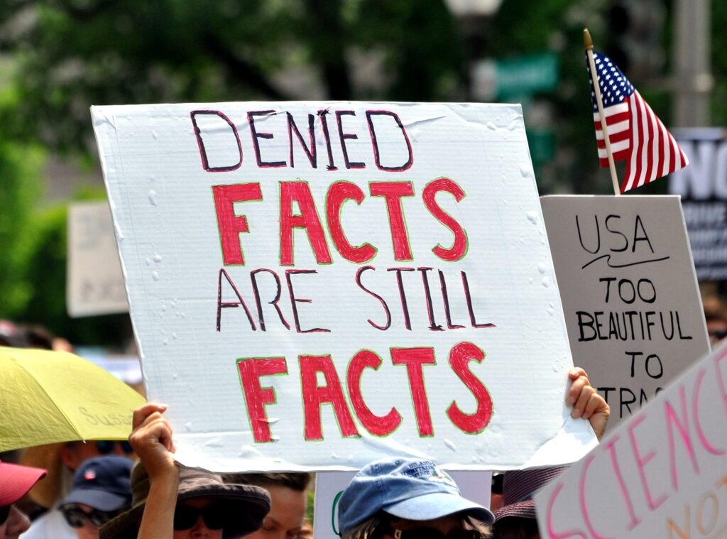 Schild auf einer Demo mit "Denied Facts are still Facts"