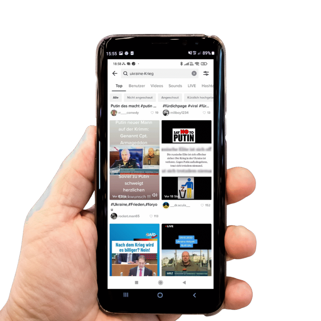 Hand mit Handy auf dem Tiktok-Suchergebnisse für ''ukraine-Krieg'' zu sehen sind