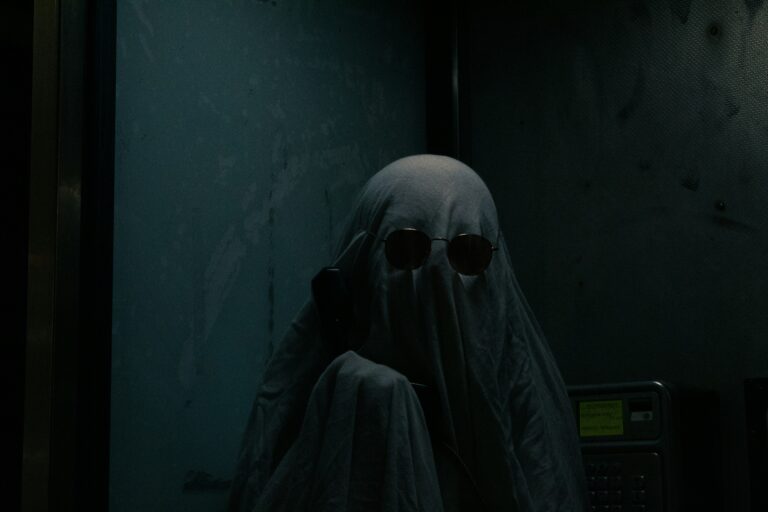 Eine als Geist verkleidete Person, mit Sonnenbrille und Telefon in der Hand