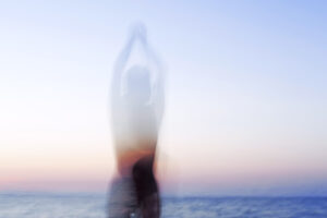 Eine verschwommene Silhouette in der Dämmerung, im Hintergrund das Meer