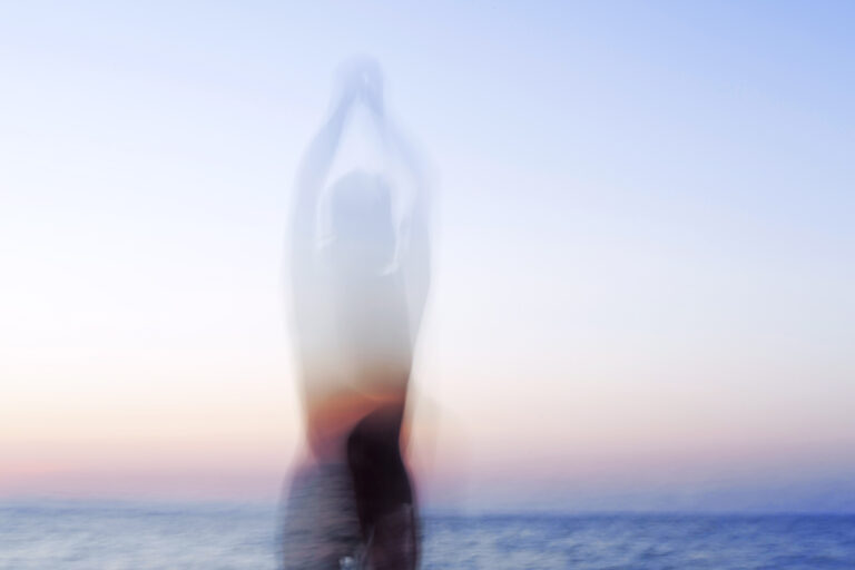 Eine verschwommene Silhouette in der Dämmerung, im Hintergrund das Meer