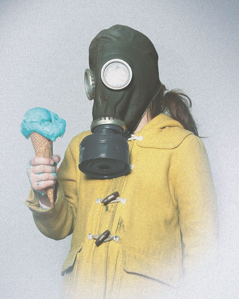 Kind mit alter Gasmaske auf, welches ein Eis in der Hand hält.