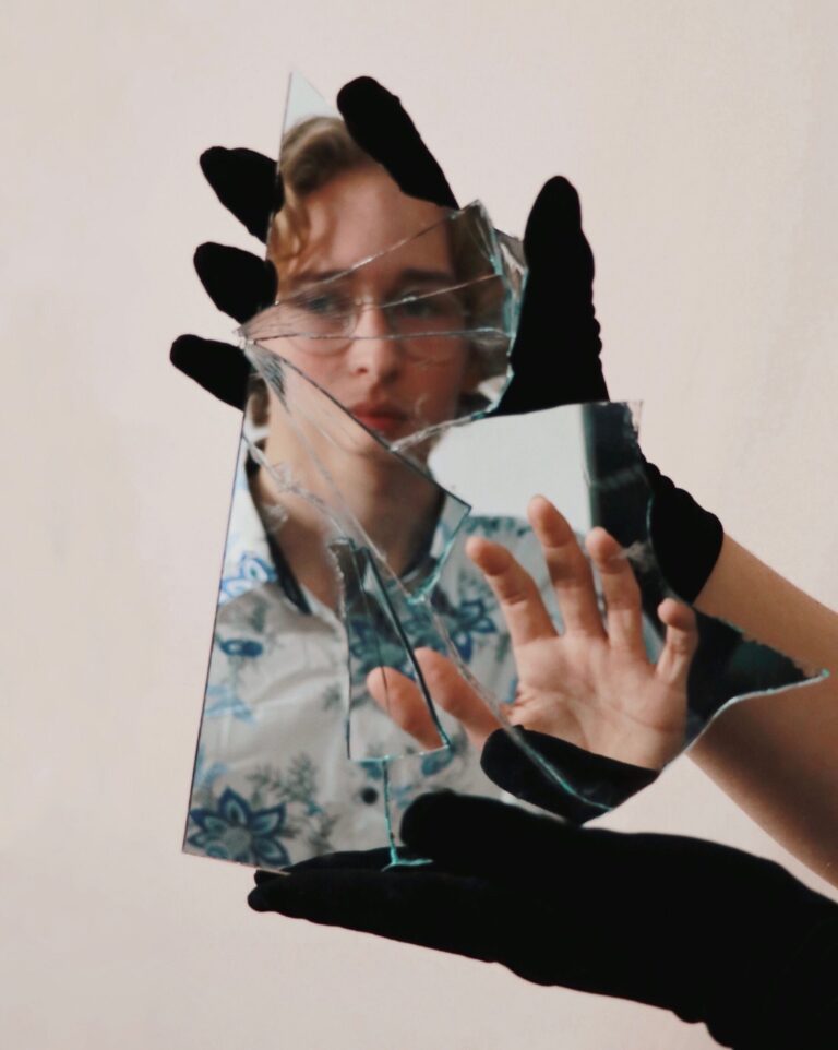 Ein zersplittertes Stück Spiegel, in dem Mann das Gesicht einer jungen Person erkennt