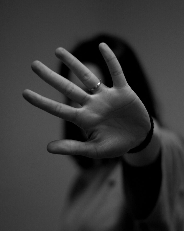 Schwarz-weiß Foto von einer Frau, die ihre Hand ausgestreckt vor die Kamera hält und die Sicht blockiert