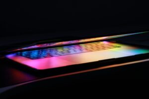 Halb aufgeklappter Laptop mit bunt reflektierendem Bildschirm