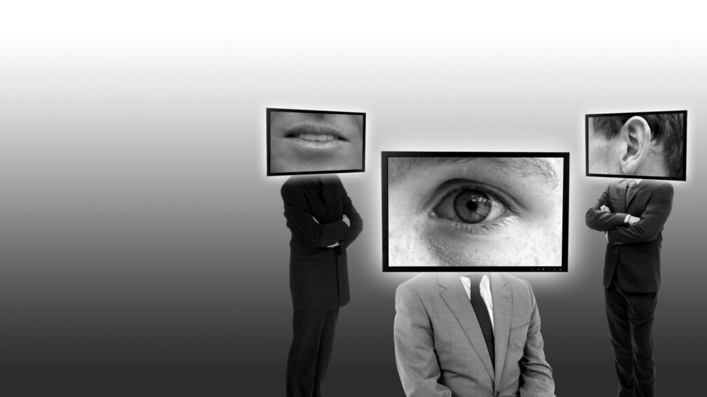 Ein schwarzwei&szlig;es Bild mit Personen, die Bildschirme als K&ouml;pfe tragen, auf denen K&ouml;rperteile abgebildet sind: Auge, Mund, Ohr