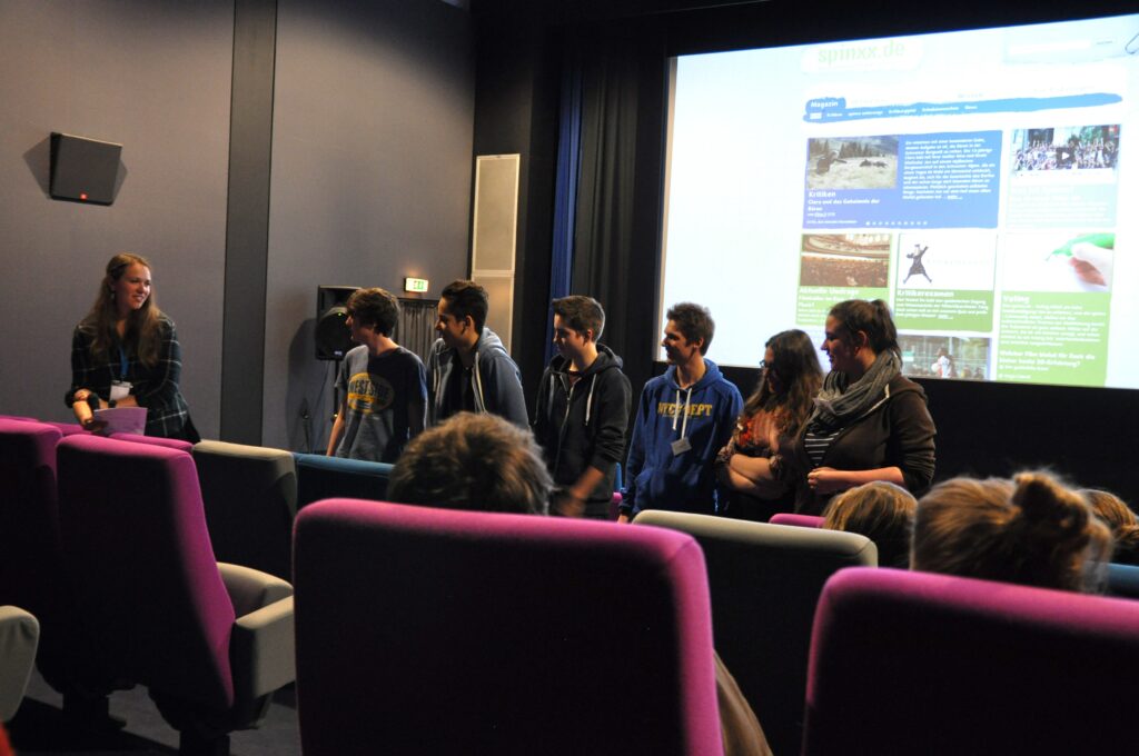 Die junge Spinxx-Redaktion aufgestellt vor der Leinwand im Kinosaal