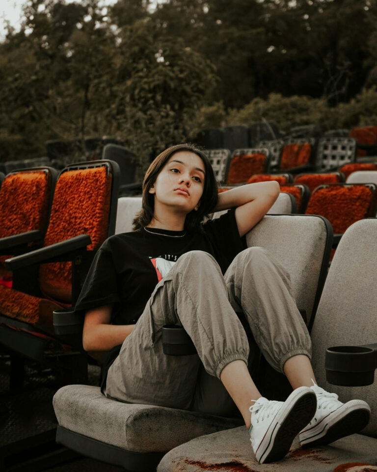 Eine junge Frau, die auf einem Kinosessel im freien sitzt, umgeben von weiteren