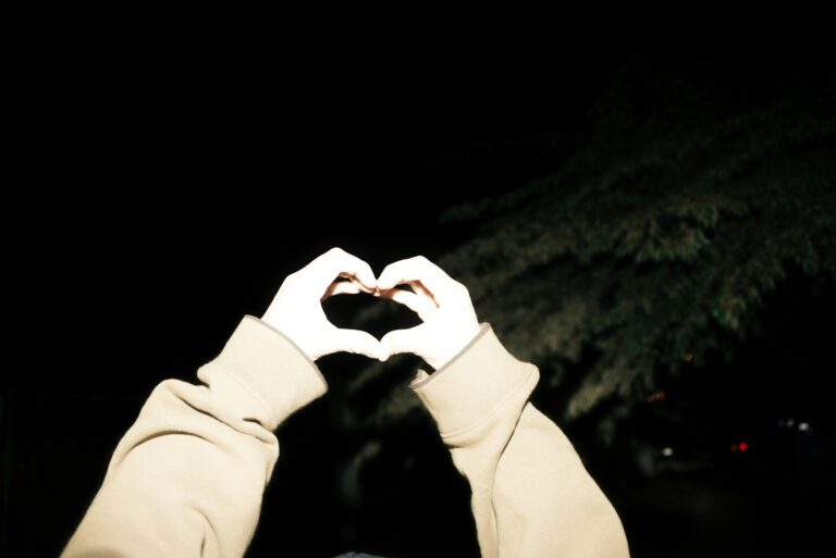 Zwei Hände formen ein Herz, die Hände sind mit einem Fotoblitz angestrahlt