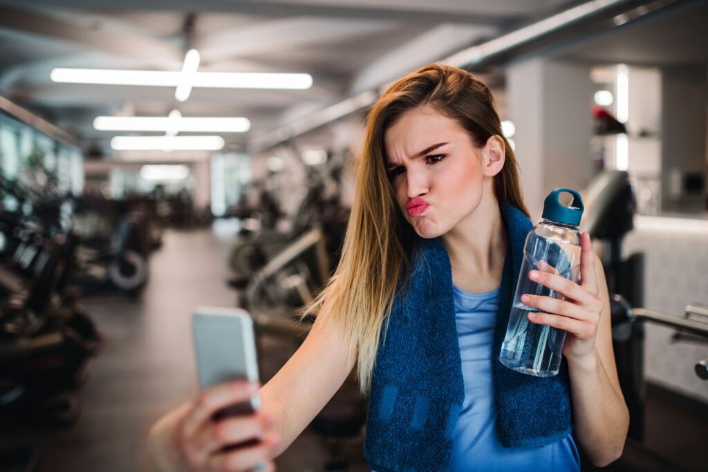 Eine junge Frau im Fitnessstudio, die ein Selfie mit Duckface macht