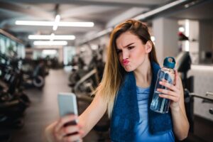 Eine junge Frau im Fitnessstudio, die ein Selfie mit Duckface macht