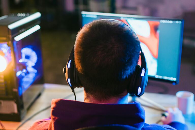 Eine Person von hinten, die mit Kopfhörern vorm Computer sitzt