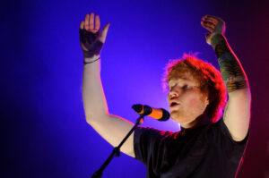 Musikstar Ed Sheeran, der mit gehobenen Armen am Mikro verformt