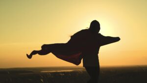 Ein Mädchen mit Superheldenumhang vor Sonnenuntergang