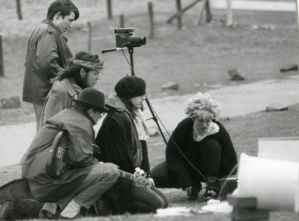 Schwarz-weiß-Foto eines Filmteams, bestehend aus 5 Personen, die gespannt auf einen Bildschirm schauen