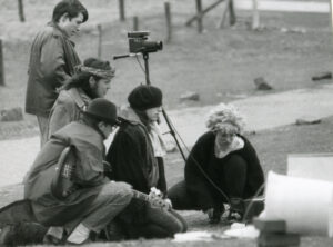 Schwarz-weiß-Foto eines Filmteams, bestehend aus 5 Personen, die gespannt auf einen Bildschirm schauen