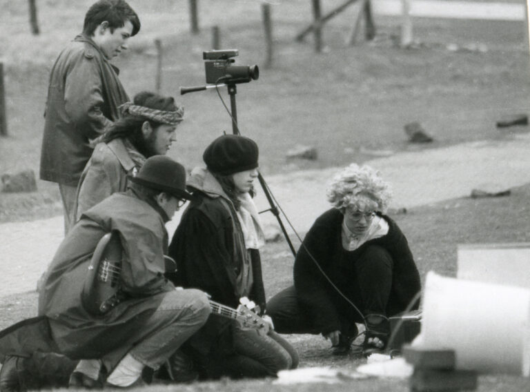Schwarz-weiß-Foto eines Filmteams, bestehend aus 5 Personen, die gespannt auf einen Bildschirm schauen