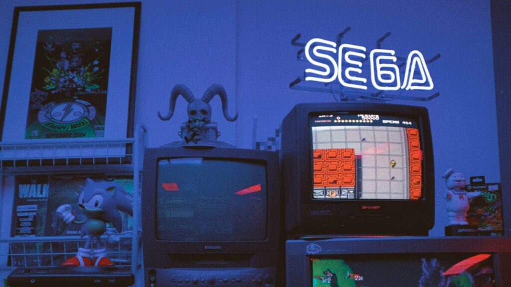 Mehrere gestapelte Röhrenfernseher, auf denen Retro-Videospiele laufen und Merchandise aus verschiedenen Videospielen