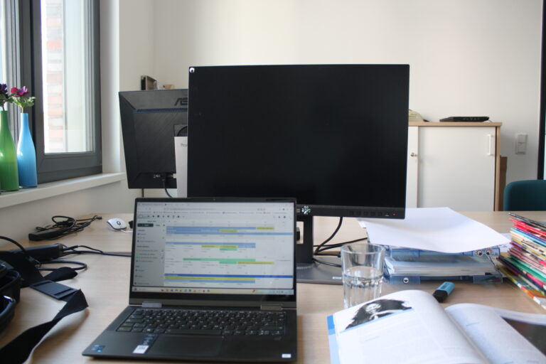 Arbeitsplatz mit Laptop und großem Bildschirm im jfc Medienzentrum